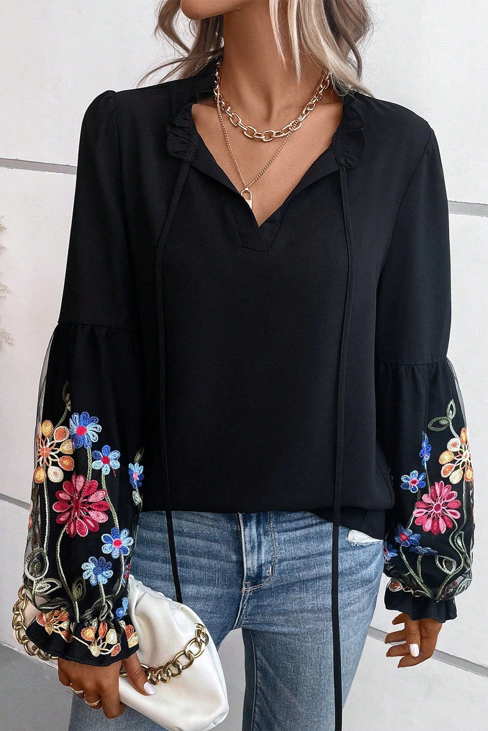 Blusa con cuello dividido y manga con volante y parche floral negra