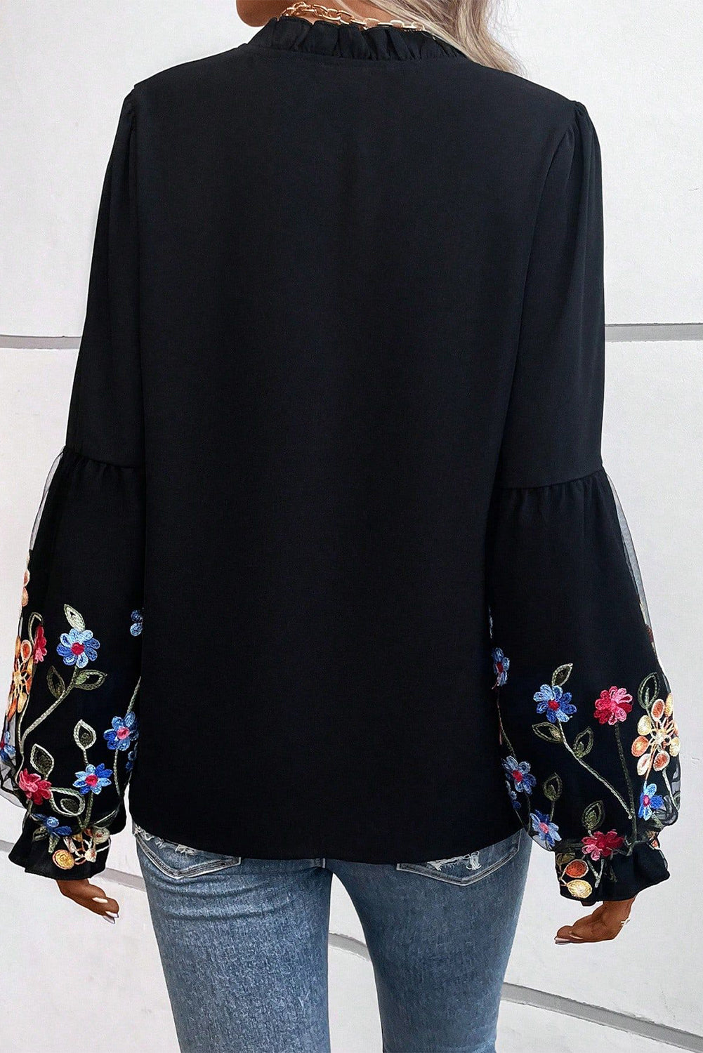 Blusa con cuello dividido y manga con volante y parche floral negra